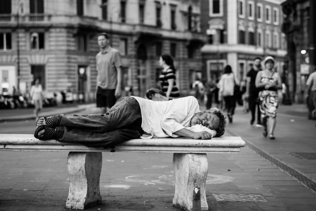 man sleeping on a bench in the street 